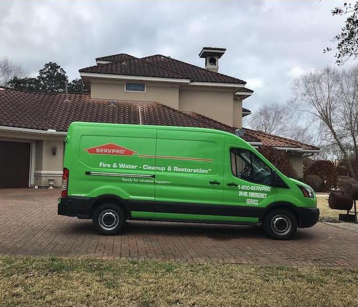 green SERVPRO van sitting in the driveway in front of a tan stucco house