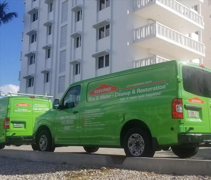 Two SERVPRO vehicles parked in front of a hotel. 