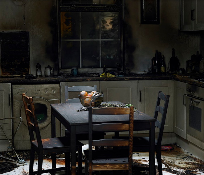 a fire damaged kitchen with soot covering the walls and furniture